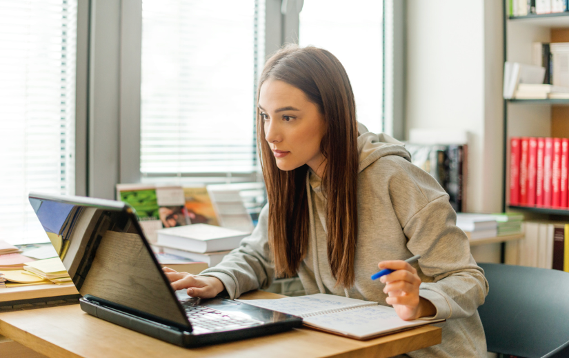 Focused woman exploring niche research tips on a laptop, taking notes for content planning and strategy.